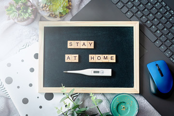 Words stay at home made of wooden blocks, concept of self quarantine at home as preventative measure against virus outbreak. Flat lay, laptop, note books, staying at home during emergency