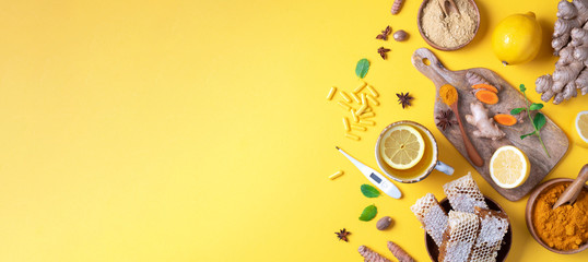 Medical care concept. Cold, flu treatment. Ginger, lemon, honey, pills, drugs, supplements, thermometer on yellow background. Natural alternative holistic approach. Top view, copy space