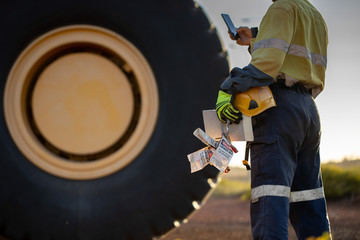 Haul truck driver wearing work uniform safety glove holding hard hat danger tags personal locks and...