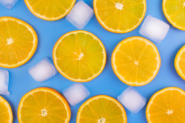 Fototapeta na wymiar Slices of orange and ice cubes on a blue background.Summer background.