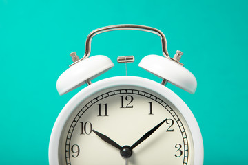 White alarm clock on a blue background. Close-up