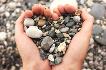 heart shaped small pebbles in female hands