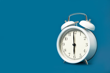 White alarm clock on a blue background. Place for text