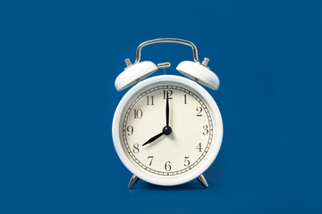 White alarm clock on a blue background. Place for text