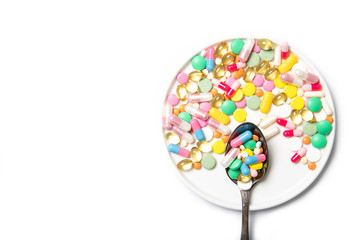 Spoon with multi-colored pills on a white background. Place for text. The medicine