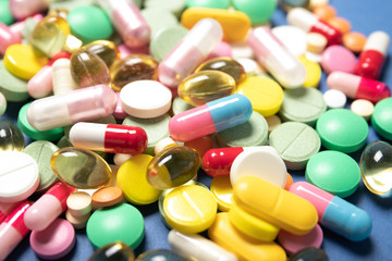 Pills and capsules on a blue background, close-up. Concept of medicine and health