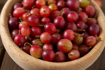 Red gooseberry in a bowl on wooden surface