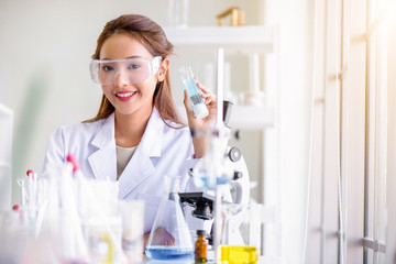 Attractive happiness scientist woman lab technician assistant analyzing sample in test tube at laboratory. Medical, pharmaceutical and scientific research and development concept.