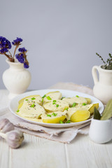 boiled potatoes in a cream cheese sauce with greens on a plate