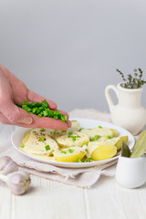 boiled potatoes in a cream cheese sauce with greens on a plate