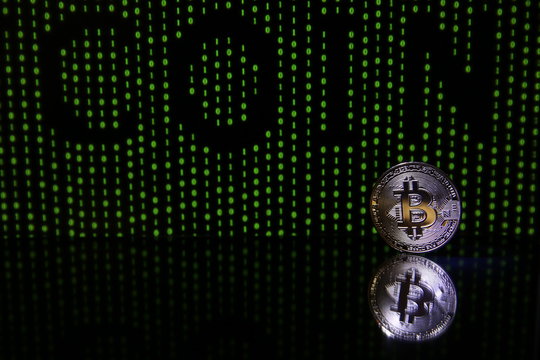 Bitcoin coin with reflection on black background with green binary code 
