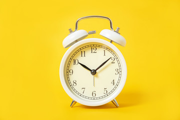 White alarm clock on a yellow background.
