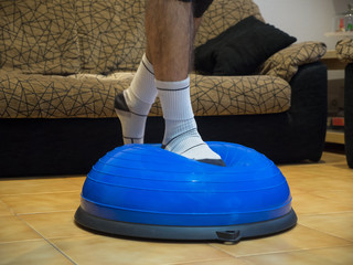 Athlete doing strength and balance exercises on a bosu ball at home.