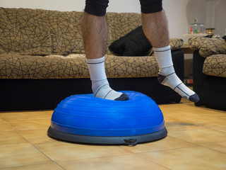 Athlete doing strength and balance exercises on a bosu ball at home.