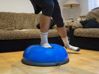 Athlete doing strength and balance exercises on a bosu ball at home.