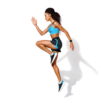 Sporty girl jumping. Photo of african american girl in fashionable sportswear on white background. Dynamic movement. Side view. Full length. Sports and healthy lifestyle