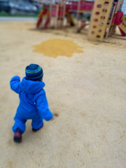 A small child in a blue jumpsuit runs across the yellow surface to the town on the Playground