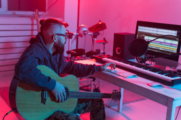 Create music and a recording studio concept - Bearded man guitarist recording electric guitar track...