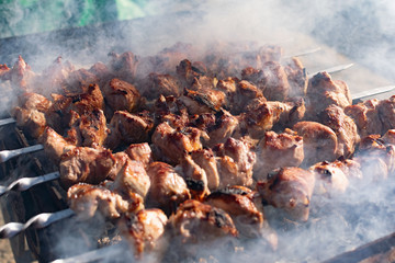 Mouth- watering skewers of pork with a toasted Golden crust and smoke flavor. Barbecue with coals in the yard in nature with cooked meat on skewers