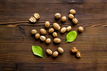 Nutmeg - whole nuts near leves - on wooden background top-down