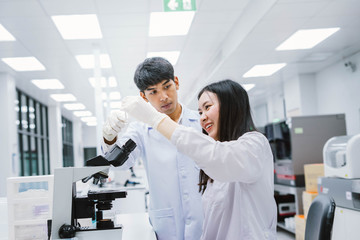 Two young medical  scientist looking at test tube in medical laboratory , select focus on young  female scientist