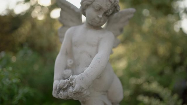 Cupids statue in the garden at evening. Handheld shot	