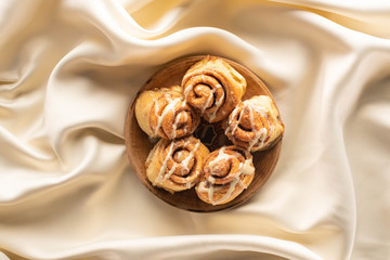 top view of fresh homemade cinnamon rolls on silk white cloth