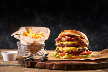 Set of hamburger and french fries. A standard set of drinks and food in the pub, beer and snacks. Dark background, fast food. Traditional american food.