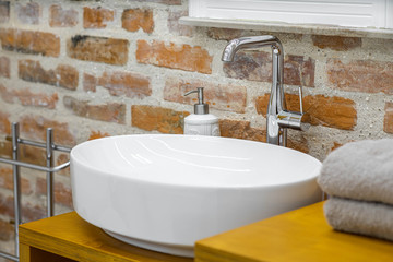 White sink in modern loft bathroom. Brick wall. Close-up.