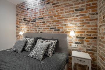 Modern loft interior of luxury bedroom with brick walls. Close-up. Pillows on the bed.