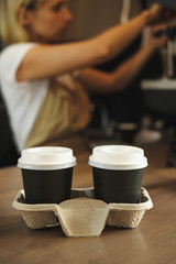 Two cups of coffee and Female barista with coffee machine on background. 