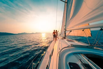 Foto auf Acrylglas Young couple enjoys sailing in the tropical sea at sunset on their yacht. © Dudarev Mikhail