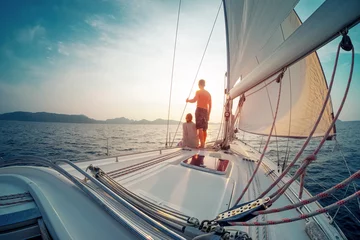 Fensteraufkleber Young couple sailing in the tropical sea at sunset on their yacht © Dudarev Mikhail