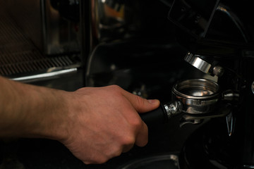barista picks up a serving of freshly ground coffee