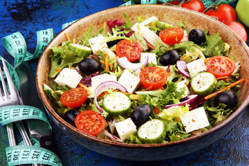 Authentic fresh salad in a stone cup with dumbbells excercise equipment, measuring tape on table. healthy lifestyles, good health Concept with fresh ingredients