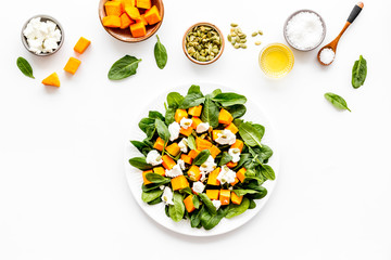 Salad with pumpkin and basil - near ingredients - on white background top-dow