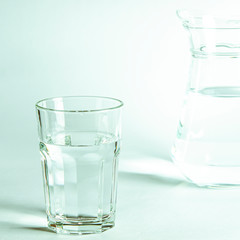 Pure clear water in a glass and jug stands on a white background