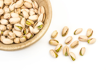 Pistachos sobre un cuenco de madera y sobre una mesa fondo blanco aislado. Vista superior. Copy space