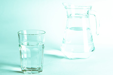 Pure clear water in a glass and jug stands on a white background