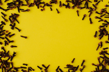 Cloves pattern on yellow background with copy space.