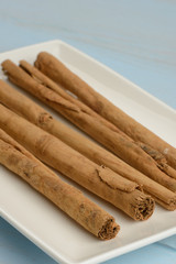 Canela en rama en un plato en la mesa azul