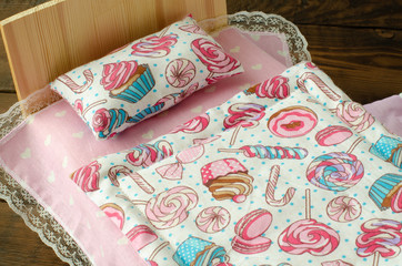 Colorful toy bed linen for dolls on wooden background