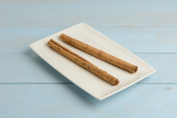 Canela en rama en un plato en la mesa azul