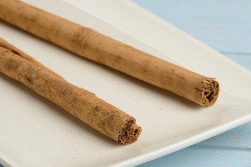 Canela en rama en un plato en la mesa azul