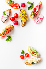 Sandwiches - set with vegetables, caviar, salami - on white background top-down copy space