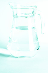 Blurred. Pure clear water in a glass and jug stands on a white background