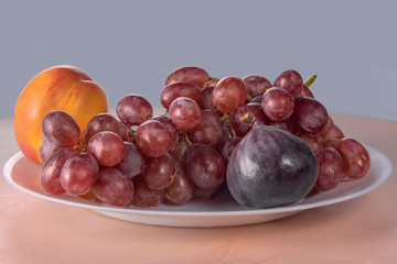 red grapes and fresh ripe fruits on a light kitchen table