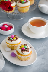 Homemade Easter vanilla cupcakes bird's nest with butter cream, chocolate and candy eggs on a dish. Easter fun food idea for kids. Vertical orientation.