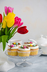 Homemade Easter vanilla cupcakes bird's nest with butter cream, chocolate and candy eggs on a dish....