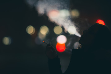 girl smokes a cigarette while walking in the night city